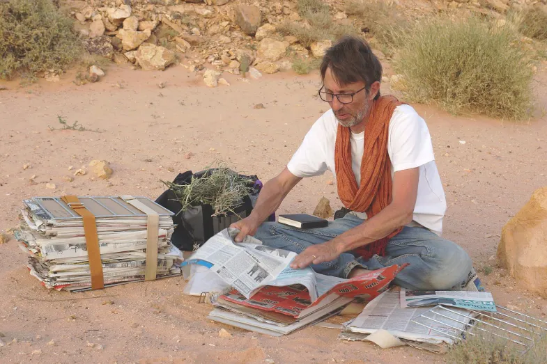 Cyrille Chatelain assis dans le sable à préparer des échantillons d'espèces récoltées