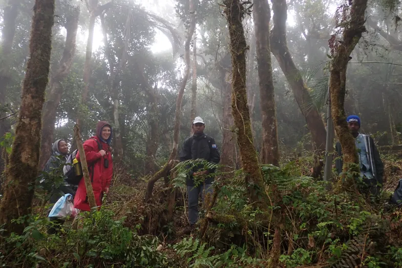 Photo de terrain en foret malgache avec deux étudiantes à gauche et deux guides au centre et à droite