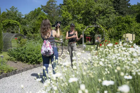 Une journaliste filme une horticultrice dans les jardins ethnobotaniques